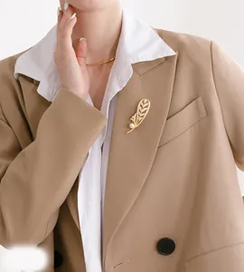 Broche élégante en plume dorée avec perle blanche sur revers de blazer kaki chic et pro