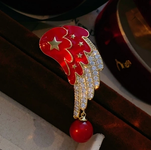 Détail macro de la broche aile d'ange avec émail rouge, étoiles dorées et strass brillants
