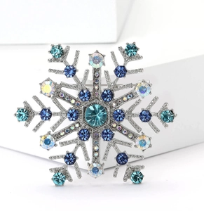 Detail einer eleganten Schneeflocken-Brosche mit blauen Kristallen auf einem Podest