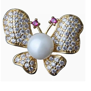 Broche papillon étincelante avec perle centrale et ailes en strass sur base dorée