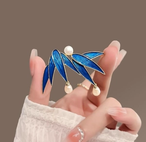 Detail of blue enamel bamboo leaf brooch with gold edges and hanging pearls