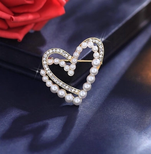 Détail de la broche cœur en perles avec base dorée et cristaux sur fond bleu texturé