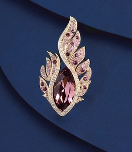 Détail macro de la broche aile dorée avec cristal violet sur papier bleu