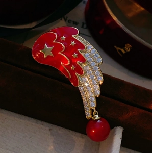 Vue détaillée d'une broche ailes d'ange en émail rouge avec étoiles dorées et cristaux