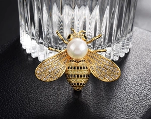 Macro shot of bee brooch with large white pearl, clear zircons and striped abdomen