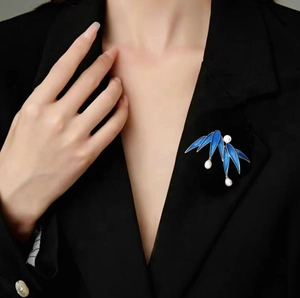 Detailed view of a navy blue leaf brooch with white pearls on a black suit lapel