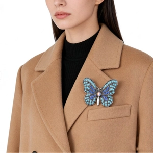 Elegante spilla a farfalla con cristalli blu su un cappotto di lana kaki per donna