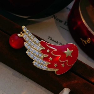 Détail d'une broche aile en émail rouge avec cristaux, étoiles dorées et pendentif