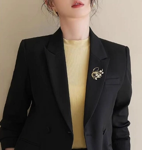 Détail d'une luxueuse broche cygne avec œil de chat et perles sur une veste noire
