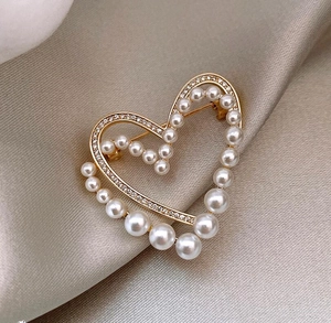 Vue détaillée de la broche double cœur avec perles blanches et cristaux brillants