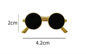 Macro view of vintage gold sunglasses brooch showing 4.2cm width and black lacquer lenses