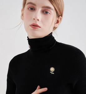 Detailed close-up of a sunflower brooch with white crystals on a black sweater