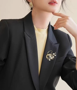Détail de la luxueuse broche cygne en opale et cristaux sur une veste de blazer noire