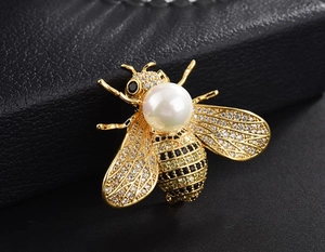 Macro shot of bee brooch with white pearl and sparkling crystals on black leather back