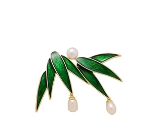 Detail view of gold bamboo leaf brooch with green enamel and three white pearls
