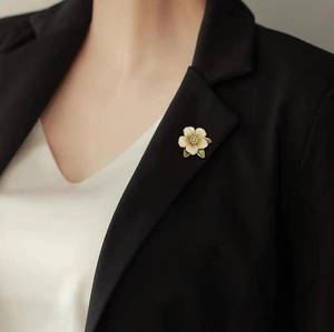 Elegante gardenia bloem broche met witte bloemblaadjes en parels op een zwart jasje