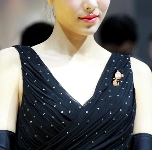 Detailed close-up of a cute cat pearl brooch pinned on a black evening dress fabric