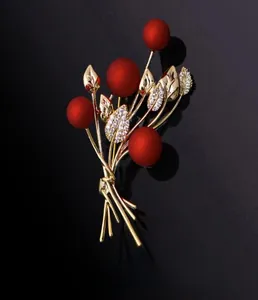 Close-up of red berry brooch with golden leaves and sparkling zircon stones inlay