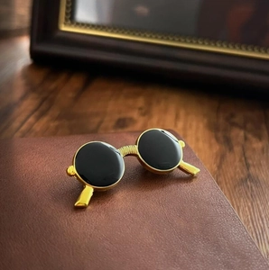 Macro shot of vintage gold sunglasses brooch pin with black lenses on leather surface