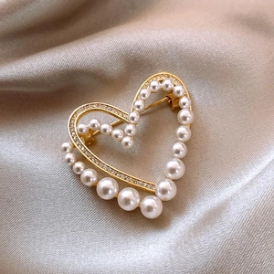 Gros plan d'une élégante broche cœur en perles avec strass brillants sur satin
