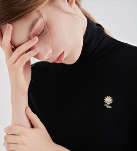 Detailed view of sunflower brooch with shimmering crystals worn on a black knit sweater