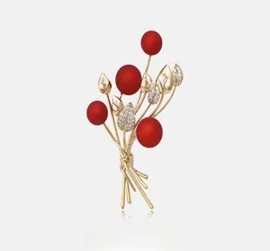 Detail of red berry brooch with gold-plated leaves and sparkling white crystals