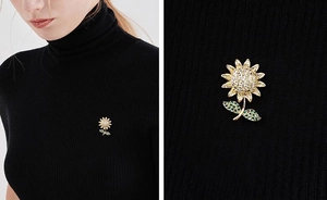 Detailed macro view of a sunflower brooch with white zircons and green leaves on black knit
