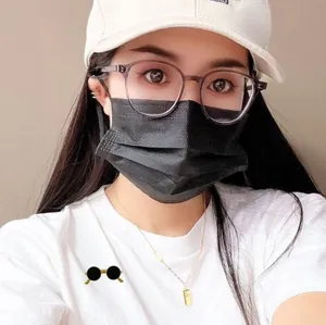 Detail showing grey translucent resin glasses styled with a white cap and gold necklace