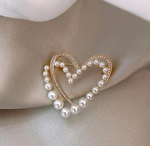 Détail d'une broche en forme de cœur avec perles et strass sur tissu en soie douce
