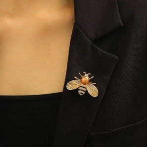 Elegant gold bee brooch with orange pearl and crystals on a black suit lapel
