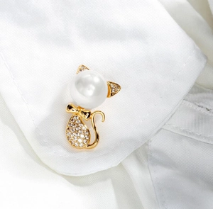 Close-up of golden cat brooch with large pearl head and sparkling crystal body details