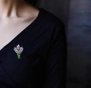 Détail d'une broche florale avec pierres précieuses lavande et vertes sur vêtement