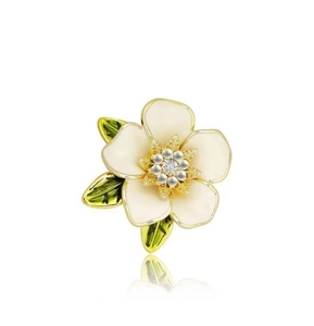 Detail van een witte emaille gardenia broche met groene bladeren en parel accenten