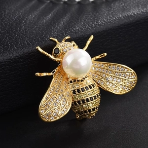 Luxurious gold bee brooch with large white pearl and sparkling crystals on a leather base