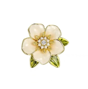 Detail van elegante emaille gardenia bloem broche met parels en groene bladeren op goud