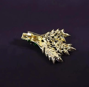 Vue détaillée du dos d'une broche feuille dorée avec fermoir à épingle et pierres vertes