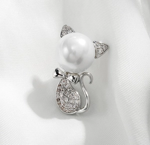 Close-up of cute cat brooch with white pearl head and zircon-studded silver body