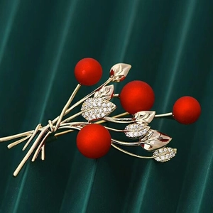 Elegant vintage red berry brooch with green leaves and gold stem on pleated background