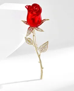 Détail macro de la broche rose rouge avec tige dorée et feuilles de cristal étincelantes