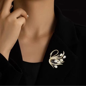 Broche cygne dorée avec pierres d'opale et cristaux portée sur un blazer noir chic
