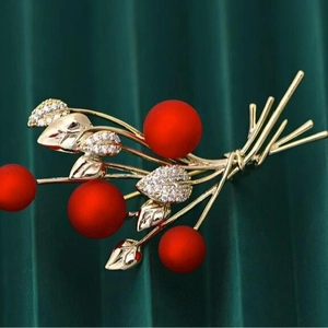 Elegant red berry brooch with gold leaves and cubic zirconia on green velvet background