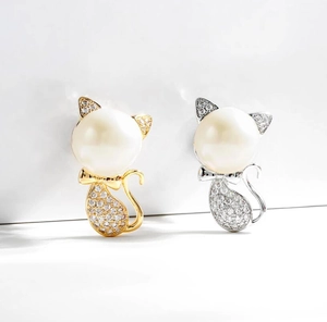 Macro detail of cute cat brooches with pearls and cubic zirconia in gold and silver