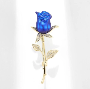 Détail macro d'une broche rose bleue élégante avec feuilles dorées et pierres zircons