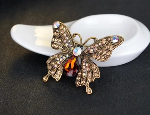 Makroaufnahme einer Vintage Schmetterling Brosche mit Strass und orangefarbenem Kristall