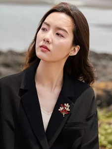 Elegant red berry and silver leaf brooch on black suit lapel with beach background