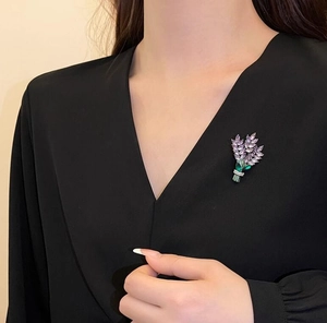 Vue détaillée d'une broche lavande avec cristaux violets sur un haut noir à col en V