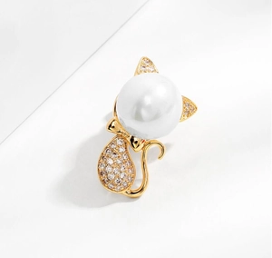 Detailed view of cat brooch with a large white pearl head and gold rhinestones