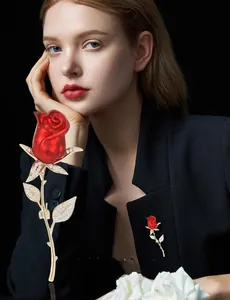 Détail d'une élégante broche rose rouge avec feuilles dorées et cristaux brillants