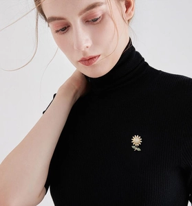 Detail of sunflower brooch with white crystals and green leaves on black sweater