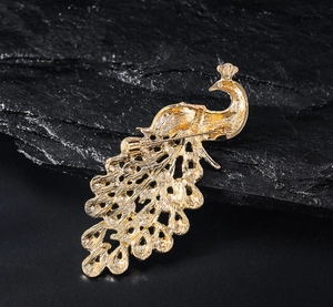 Detailed back view of a golden peacock brooch with pin fastener and metal texture